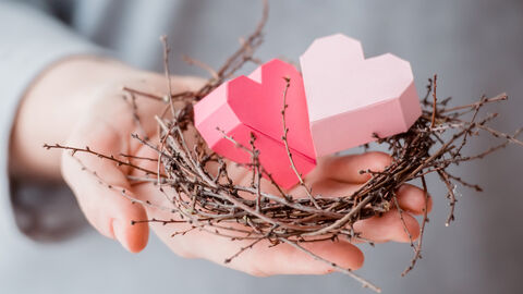 Tax benefits for spouses Hand holds two paper hearts in a nest of twigs